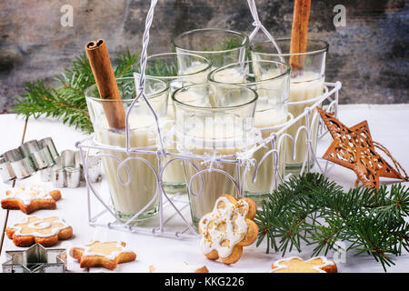 Biscotti di Natale assortiti e bicchieri di latte cocktail serviti con albero di natale ramo sul tavolo di legno. Vedere serie. Foto Stock