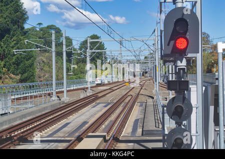 I binari della ferrovia che va alla città come si vede da una stazione piattaforma. Foto Stock