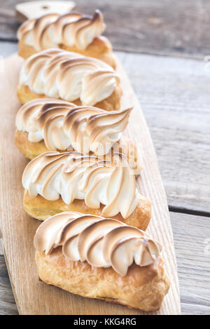 Eclairs con cagliata di limone e meringa sulla tavola di legno Foto Stock