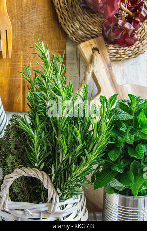 Cucina rurale interno bianco listone di legno appeso a parete taglieri biancheria utensili stringa di peperoni secchi Erbe fresche di timo rosmarino menta in ba Foto Stock