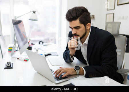 Giovane architetto bello lavorare sul computer portatile in ufficio Foto Stock