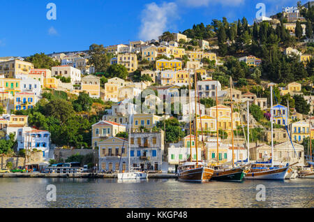 Barche ormeggiate lungo il panoramico lungomare di Yialos città sull isola di Symi, Dodecaneso, Grecia Foto Stock