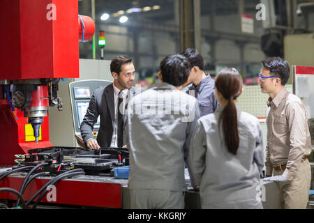 Imprenditore e ingegneri di controllo macchina in fabbrica Foto Stock