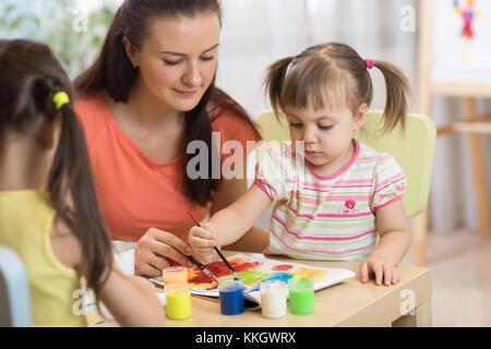 Pittura per bambini in età prescolare. insegnante aiuta da bambina. Foto Stock