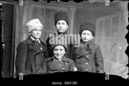 La fotografia intitolata "Patru copii cu caciuli" scattata il 14 dicembre 2013 mostra quattro bambini che indossano cappelli. L'immagine cattura un momento della vita quotidiana in un ambiente rurale, sottolineando l'infanzia e la cultura locale. Foto Stock