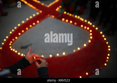 Kathmandu, Nepal. 30 nov, 2017. Una donna nepalese detiene una candela intorno a un nastro rosso acceso con candele alla vigilia della giornata mondiale contro l Aids a Kathmandu, Nepal giovedì 30 novembre, 2017. Giornata mondiale dell Aids è osservata per la sensibilizzazione e il sostegno a coloro che vivono con l hiv. Credito: skanda gautam/zuma filo/alamy live news Foto Stock