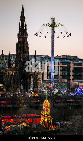 Edimburgo, Scozia, Regno Unito, 30 novembre 2017. Edimburgo celebrazioni di Natale Mercatini di Natale e giostre, con una star flyer in azione accanto a Scott.Un monumento nei giardini di Princes Street e a Hester Skelter in primo piano. Il centro della città è illuminato con splendide luci colorate al tramonto di una sera d'inverno Foto Stock