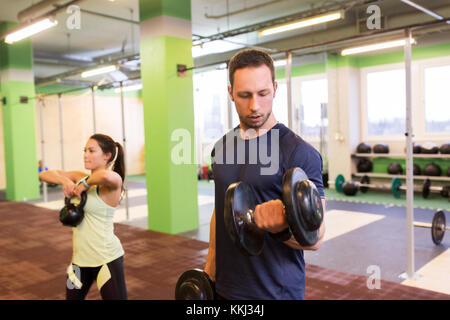 Uomo e donna con kettlebell esercizio in palestra Foto Stock