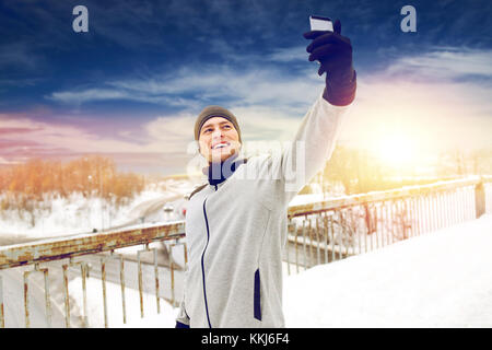 L'uomo prendendo selfie con lo smartphone in inverno Foto Stock