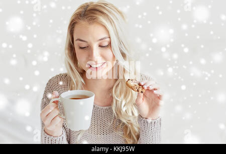 Donna felice con tè e biscotti nel letto di casa Foto Stock