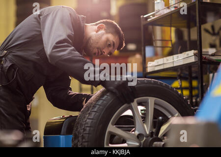 Auto bilanciamento meccanico auto ruota in officina Foto Stock