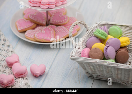 I cookie di rosa a forma di cuore su di una piastra e di pasticceria in un cesto di vimini su assi di legno il giorno di San Valentino Foto Stock