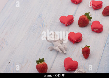 I cookie di colore rosso a forma di cuore le fragole e decorate con angelo su assi di legno il giorno di san valentino Foto Stock