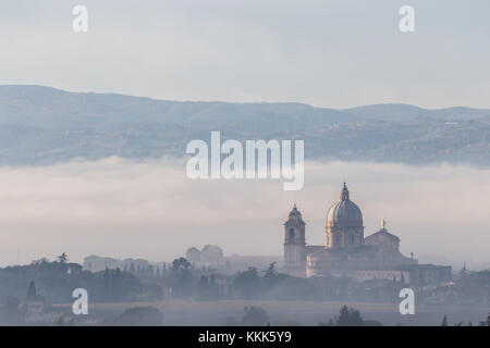 Splendida vista su Santa Maria degli Angeli chiesa papale (Assisi) nel mezzo della nebbia all'alba Foto Stock