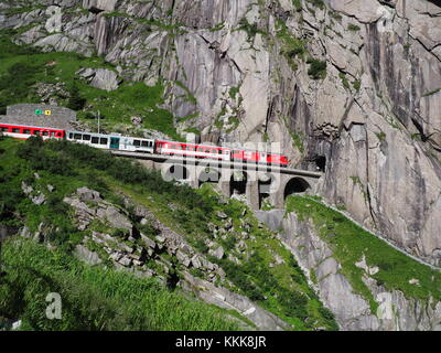 ANDERMATT, Svizzera Europa su luglio 2017: Express San Gottardo treno su Teufelsbruecke, Devil's ponte ferroviario e tunnel, Alpi svizzere. Foto Stock