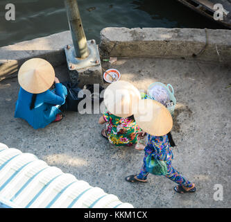 Ben tre, vietnam - il 2 febbraio 2016. donne vietnamita con il cappello conico di vendita molti frutti tropicali al mercato nel delta del Mekong, Vietnam. Foto Stock