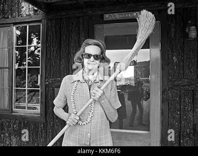 Una donna anziana che indossa una parrucca e tenendo una scopa. Foto Stock