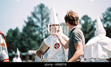 Questa potente fotografia del 1986 mostra Bruce Larsen che affronta un membro del Ku Klux Klan ad Auburn, Alabama. L'immagine cattura un momento di intensa tensione sociale e politica durante il movimento per i diritti civili, evidenziando questioni di disuguaglianza razziale e resistenza nel Sud degli Stati Uniti. Foto Stock