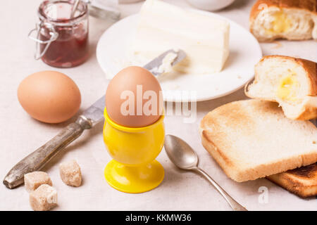 La prima colazione con uova e pane tostato con la marmellata e burro sul tessile bianco Foto Stock