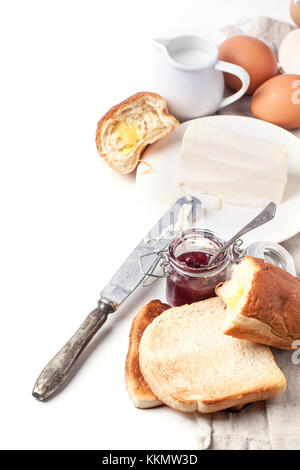 La prima colazione con uova e pane tostato con la marmellata e burro su bianco. Vedere serie. Foto Stock