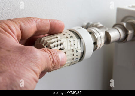 Primo piano sulla mano d'uomo la regolazione della valvola del termostato Foto Stock