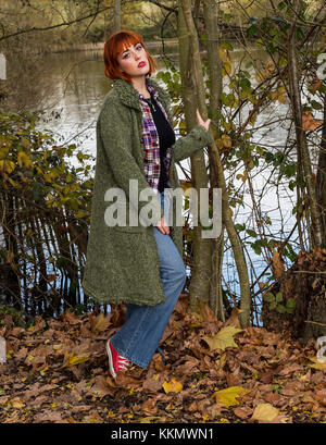 Ragazza camminare sulla strada forestale in autunno con foglie Foto Stock