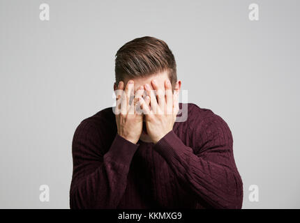 Ritratto di un giovane uomo bianco con le mani che coprono il suo volto Foto Stock