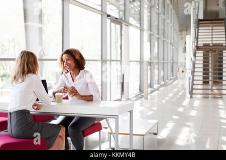 Due giovani imprenditrici in occasione di una riunione, parlando Foto Stock