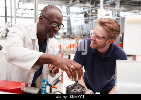 Consulenza tecnico di un maschio di apprendista in una fabbrica, close up Foto Stock