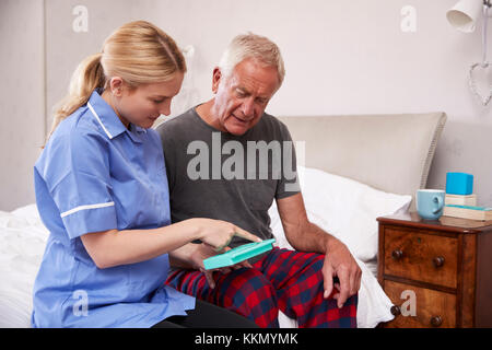 Infermiere Senior aiuta l uomo a organizzare i medicamenti sulla Home Visita Foto Stock
