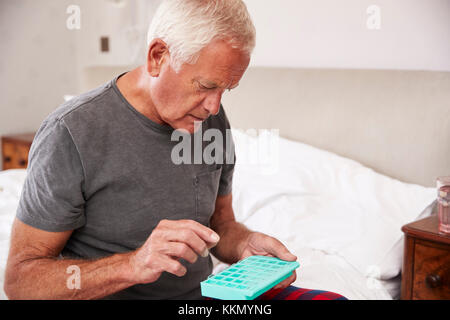 Senior uomo seduto sul letto di casa la somministrazione dei farmaci Foto Stock