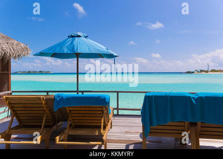 Vista dal terrazzo del bungalow alle Maldive. Sul ponte ci sono sedie a sdraio e ombrellone. Si tratta di una splendida vista sul mare, il wate Foto Stock