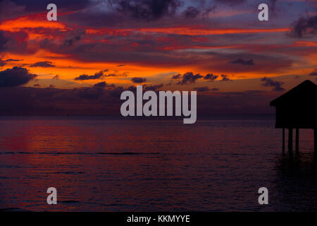 Silhouette di un bungalow sul mare di fronte al tramonto alle Maldive. Il bungalow è situato sul lato destro del telaio. Vi è un sorprendente Foto Stock