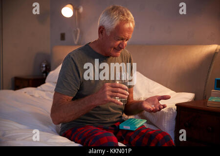 Senior uomo seduto sul letto di casa la somministrazione dei farmaci Foto Stock