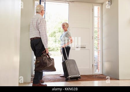 Coppia senior con bagagli di uscire di casa per le vacanze Foto Stock