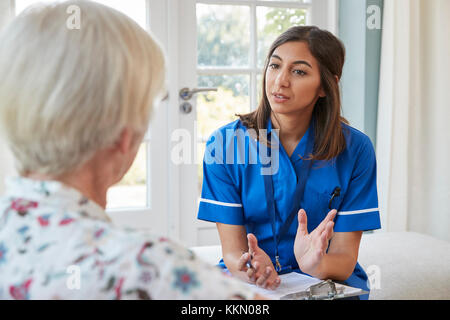 Senior Donna che parla ai giovani care infermiere su home visita Foto Stock