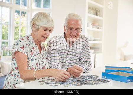 Coppia senior facendo un puzzle a casa Foto Stock