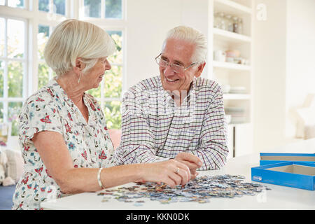 Coppia senior facendo un puzzle a casa Foto Stock