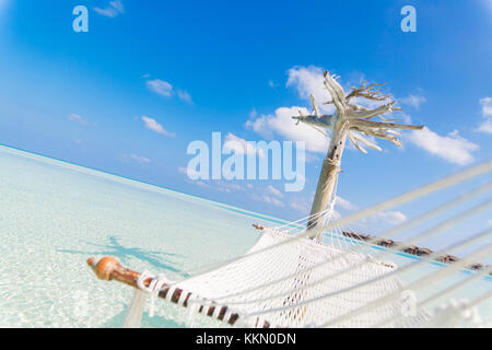 Amaca attesa da un albero bianco in un profondo e limpido mare sulla laguna delle Maldive. Foto Stock