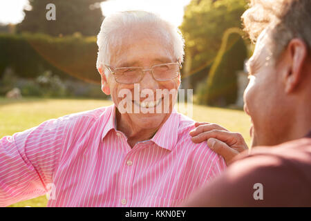 Senior uomo e figlio adulto seduto in giardino, vicino fino Foto Stock
