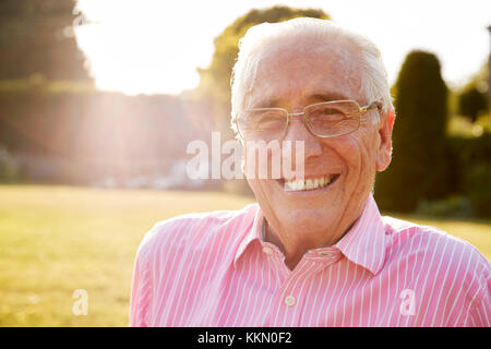 Senior l uomo nel giardino di sorridere alla telecamera, close up Foto Stock