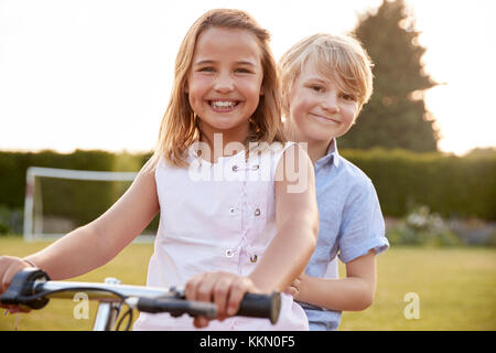 Due bambini di una bicicletta in giardino Foto Stock