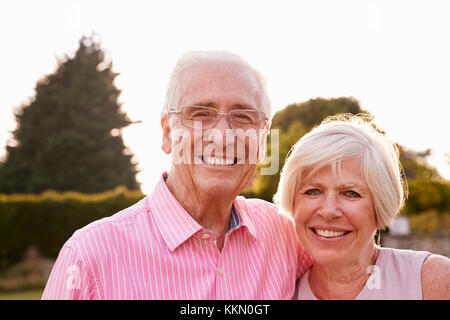 Coppia senior in giardino a sorridere alla telecamera, close up Foto Stock