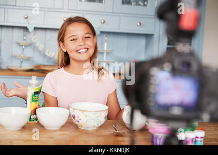 Pre-teen girl blog video in cucina sorride alla telecamera Foto Stock