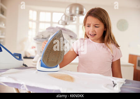 Giovane ragazza bruciare accidentalmente t shirt con ferro Foto Stock