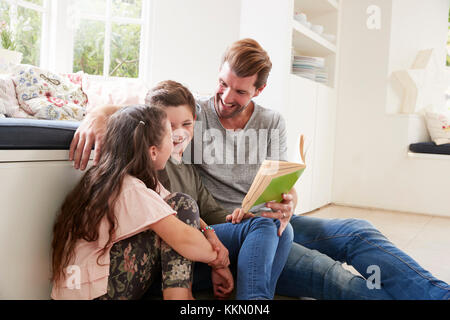 Father Reading Book With Son And Daughter At Home Foto Stock