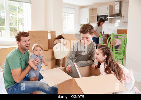 I bambini aiutano i genitori a disimballare sul movimento in giorno Foto Stock