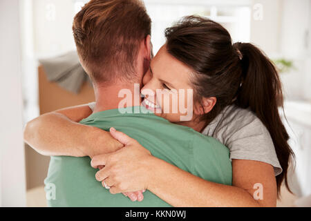 Amare giovane celebrando con un abbraccio a casa Foto Stock