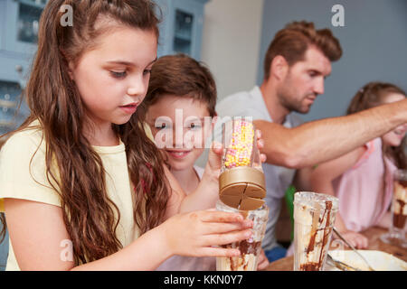 Padre produrre gelati sundaes con i bambini a casa Foto Stock