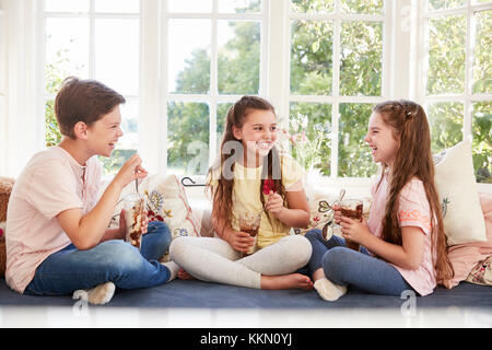 I bambini seduti sul sedile della finestra a mangiare il gelato Sundaes Foto Stock